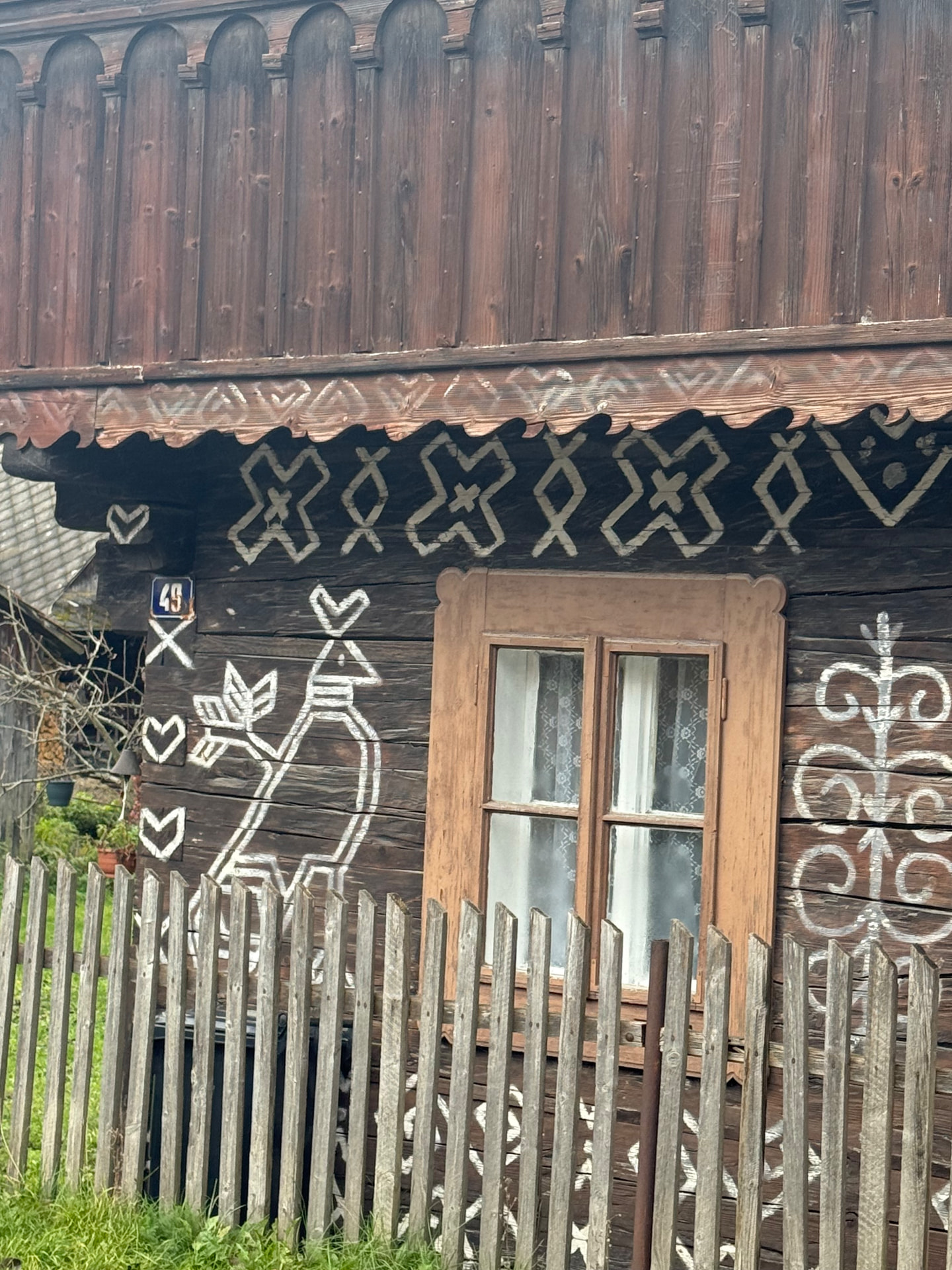 Traditional wooden house with painted folk decorative motifs and a wooden fence