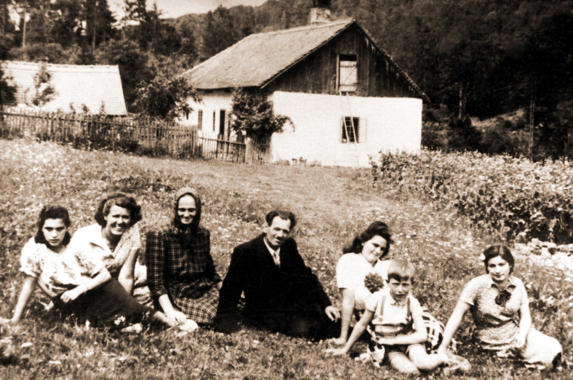 Historical archival photograph of the Huncokar community gathered in front of a traditional wooden house in the Little Carpathians