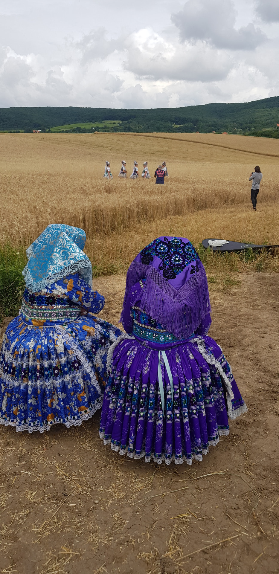 Ženy v tradičnom kroji sediace pri obilnom poli počas folklórneho podujatia