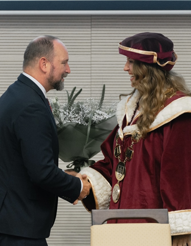 Katarína Slobodová Nováková in burgundy rectorial academic gown shaking hands during a formal university ceremony