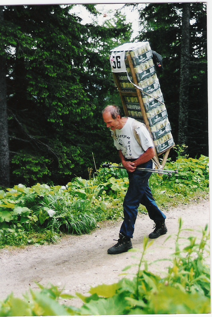 Contemporary mountain porter carrying a large load on a Tatras forest path