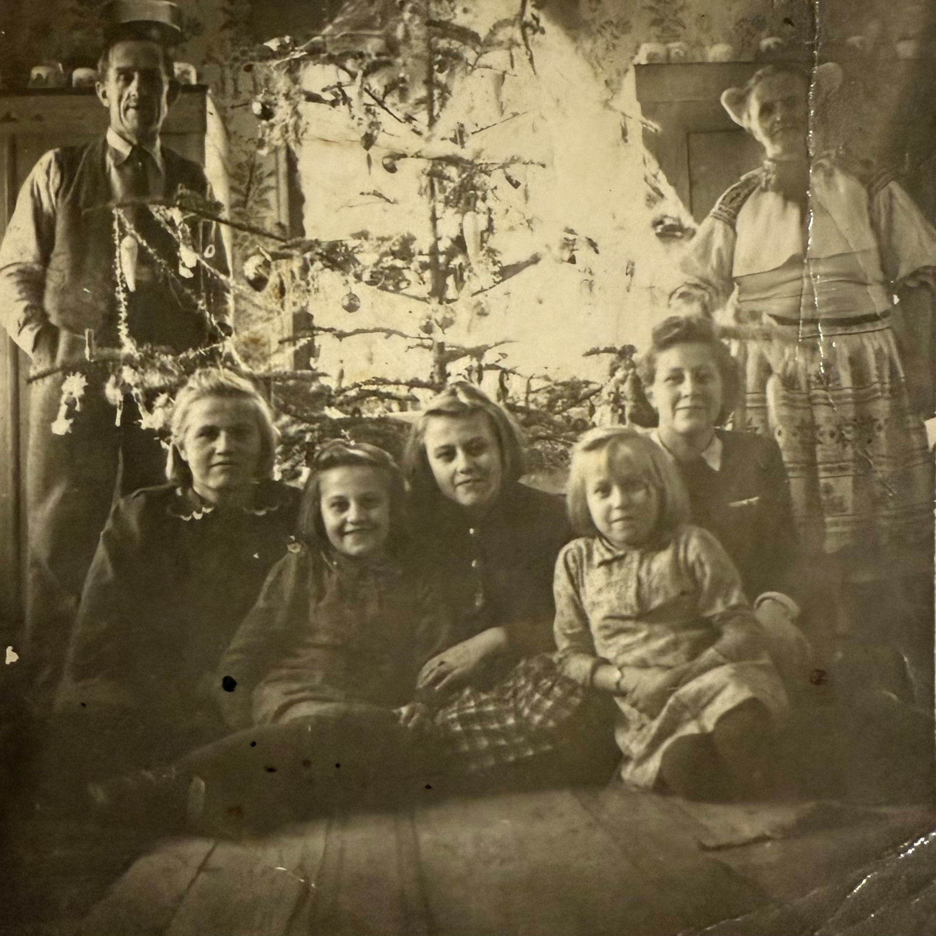 Historical family photograph of several generations gathered around a decorated Christmas tree