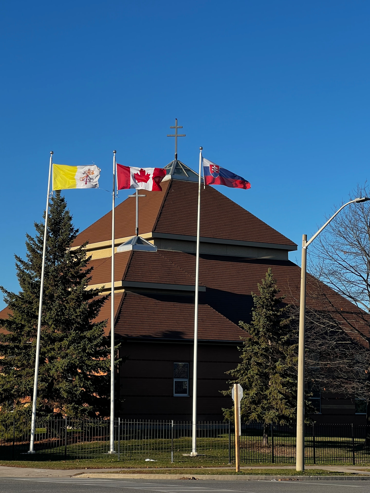 Slovak, Canadian and Vatican flags flying in front of a Slovak parish in Canada